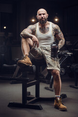 Fototapeta na wymiar brutal tattooed man in the gym drinking water