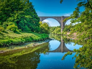 Fototapeta na wymiar A bright summers day in Washington, UK with the Victoria Viaduct casting its reflection across the River Wear