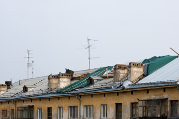 Roof repairs of an apartment building.  The roof collapsed under the weight of snow. Damaged falling roof and chimney on sunny day with clear blue sky.