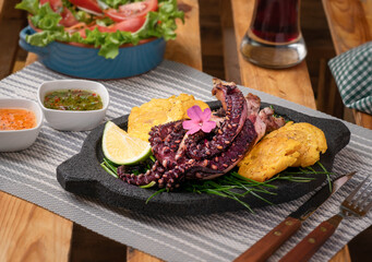 Roasted octopus with patacones, on a bed of chives, lemon, chimichurri sauce, lettuce and tomato salad and a glass of Jamaican water.