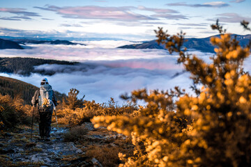 Peregrino recorriendo el camino primitivo de santiago sobre un mar de nubes y con la concha en...