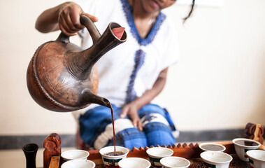 Closeup of womans hand as she serves coffee from a traditional pot in Ethiopia