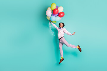 Fototapeta na wymiar Funky jumping guy hold colorful helium balloons rise up air wear formal outfit isolated on turquoise background