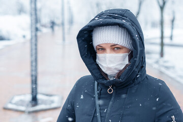 Fototapeta na wymiar Portrait of a woman wearing a medical protective mask on her face in winter, Covid-19 coronavirus pandemic, virus protection