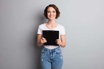 Photo of attractive cheerful young businesswoman hold clipboard checklist smile wear casual outfit isolated over grey color background