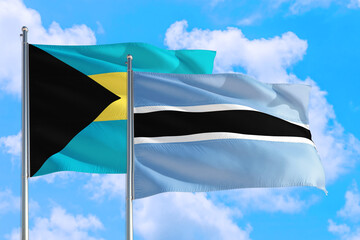 Botswana and Bahamas national flag waving in the windy deep blue sky. Diplomacy and international relations concept.