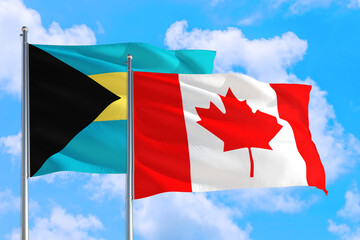 Canada and Bahamas national flag waving in the windy deep blue sky. Diplomacy and international relations concept.
