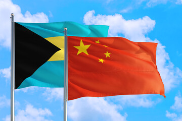 China and Bahamas national flag waving in the windy deep blue sky. Diplomacy and international relations concept.
