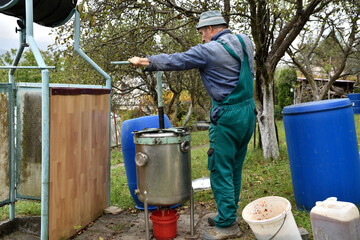 The fruit farmer rotates the press by hand while pressing the apples into fruit must