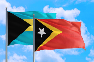 East Timor and Bahamas national flag waving in the windy deep blue sky. Diplomacy and international relations concept.
