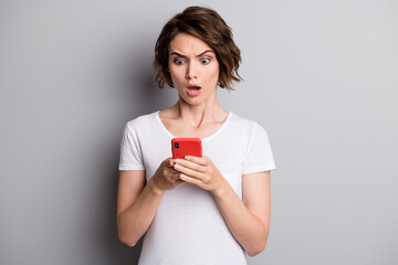 Photo of young woman hold cellphone amazed shocked surprised bad comment news isolated over grey color background