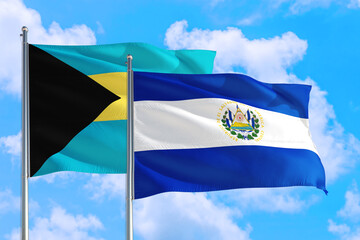 El Salvador and Bahamas national flag waving in the windy deep blue sky. Diplomacy and international relations concept.