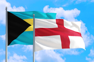 England and Bahamas national flag waving in the windy deep blue sky. Diplomacy and international relations concept.