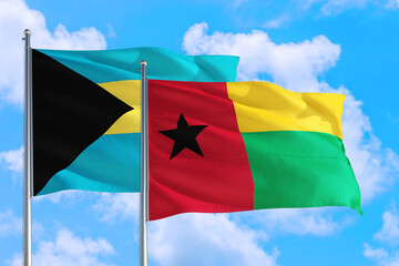 Guinea and Bahamas national flag waving in the windy deep blue sky. Diplomacy and international relations concept.