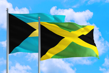 Jamaica and Bahamas national flag waving in the windy deep blue sky. Diplomacy and international relations concept.