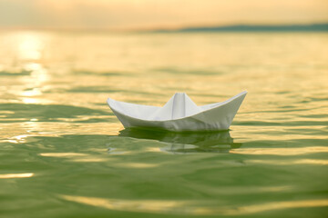 paper boat on water at sunset