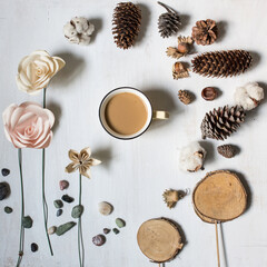 Fototapeta na wymiar Creative flat lay mock up from recycled and natural elements: origami paper roses, pebbles, wood decor, cones, hazelnuts and a coffee cup. Minimal top view for blog mood image or holiday card.