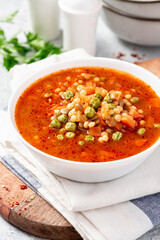 Vegetarian soup with vegetables, green peas, couscous (ptitim paste) and lentils in a white bowl close-up. Maghreb soup berkoukes. North African cuisine.