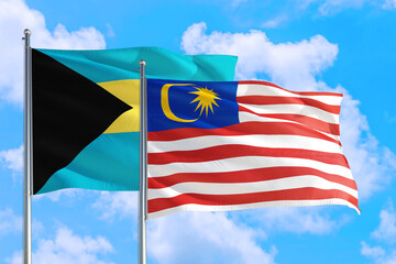 Malaysia and Bahamas national flag waving in the windy deep blue sky. Diplomacy and international relations concept.