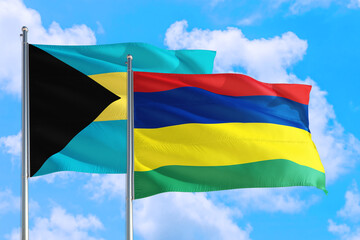 Mauritius and Bahamas national flag waving in the windy deep blue sky. Diplomacy and international relations concept.