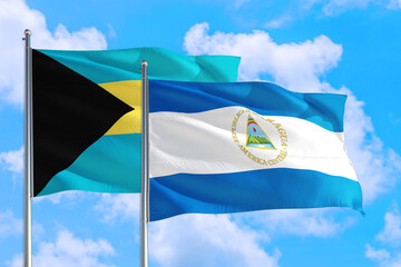 Nicaragua and Bahamas national flag waving in the windy deep blue sky. Diplomacy and international relations concept.