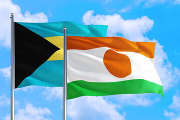 Niger and Bahamas national flag waving in the windy deep blue sky. Diplomacy and international relations concept.