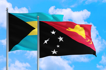 Papua New Guinea and Bahamas national flag waving in the windy deep blue sky. Diplomacy and international relations concept.