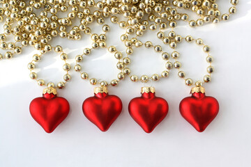 Red hearts and beads for the Christmas tree on a white background. 2022 New Year. There is room for text. Winter holidays pattern.