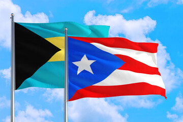 Puerto Rico and Bahamas national flag waving in the windy deep blue sky. Diplomacy and international relations concept.