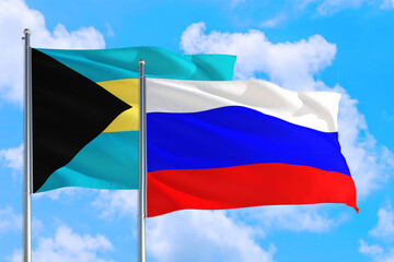 Russia and Bahamas national flag waving in the windy deep blue sky. Diplomacy and international relations concept.