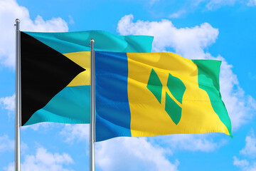 Saint Vincent And The Grenadines and Bahamas national flag waving in the windy deep blue sky. Diplomacy and international relations concept.