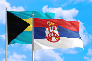 Serbia and Bahamas national flag waving in the windy deep blue sky. Diplomacy and international relations concept.