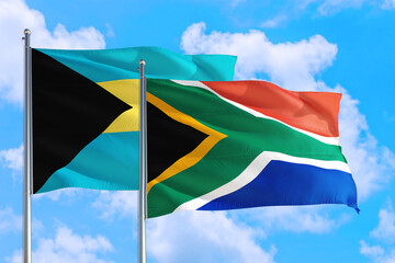 South Africa and Bahamas national flag waving in the windy deep blue sky. Diplomacy and international relations concept.