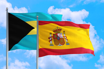 Spain and Bahamas national flag waving in the windy deep blue sky. Diplomacy and international relations concept.