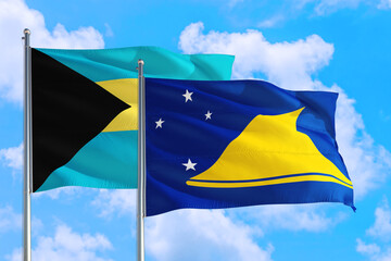 Tokelau and Bahamas national flag waving in the windy deep blue sky. Diplomacy and international relations concept.