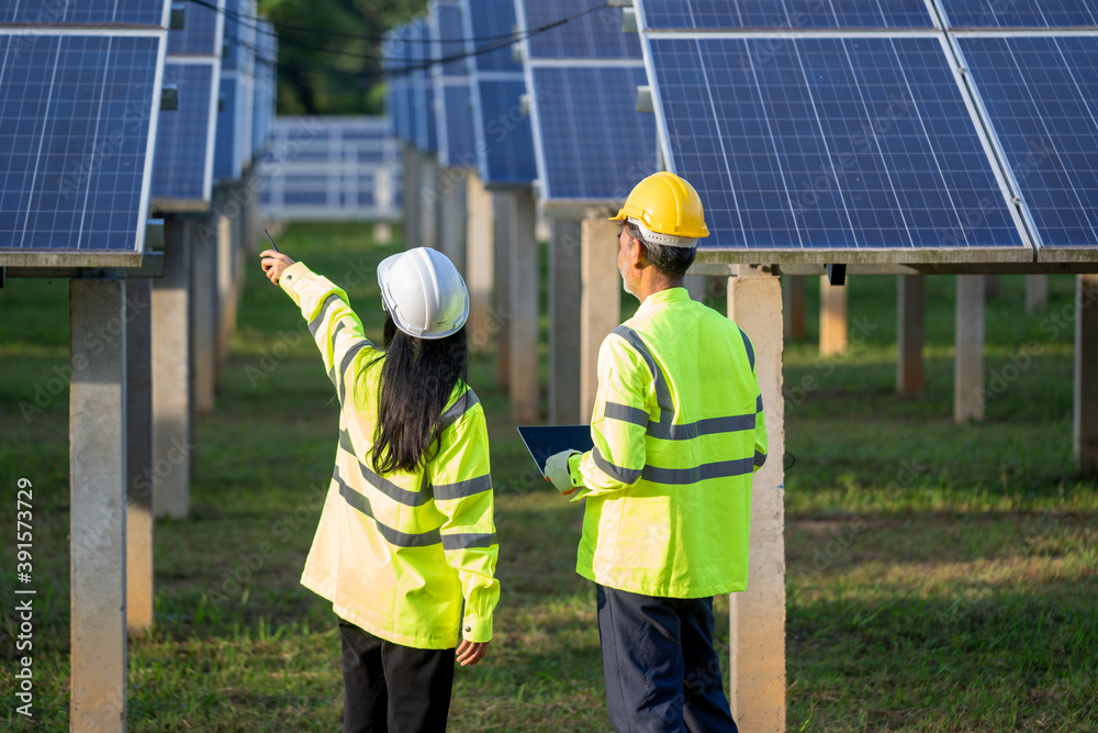 Poster Technicians and engineer in long sleeve shirts reflective vests and hard hats discussing something about solar panel power,Solar power plant to innovation of green energy for life.