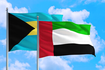 United Arab Emirates and Bahamas national flag waving in the windy deep blue sky. Diplomacy and international relations concept.