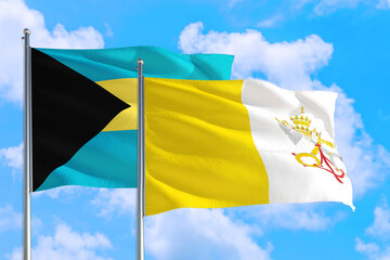 Vatican City and Bahamas national flag waving in the windy deep blue sky. Diplomacy and international relations concept.