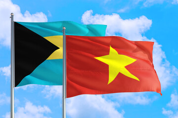 Vietnam and Bahamas national flag waving in the windy deep blue sky. Diplomacy and international relations concept.