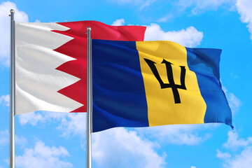 Barbados and Bahrain national flag waving in the windy deep blue sky. Diplomacy and international relations concept.