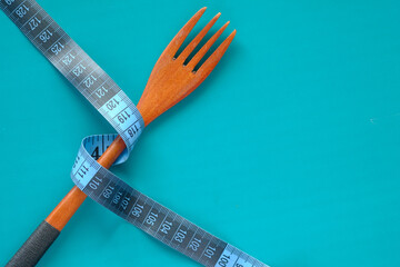 fork with measurement tape on color background 