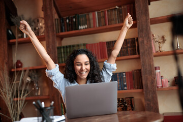 Excited young female feeling ecstatic using laptop