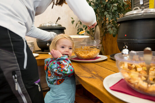 Cute girl with her mother at food buffet getting soup.