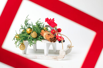 Toy wooden sleds painted white with a Christmas tree decorated with Christmas toys.