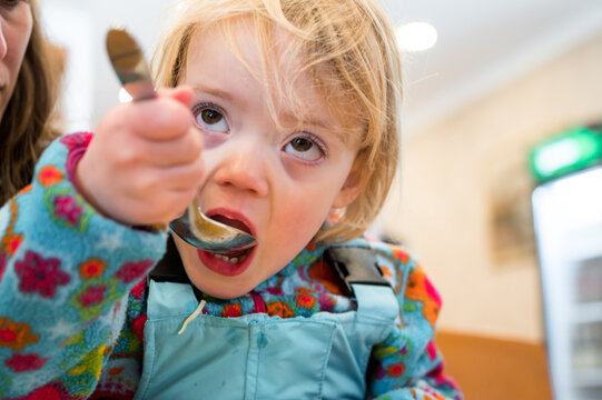 Cute blonde girl eating beef noodle soup in a restaurant with her mother. - Powered by Adobe