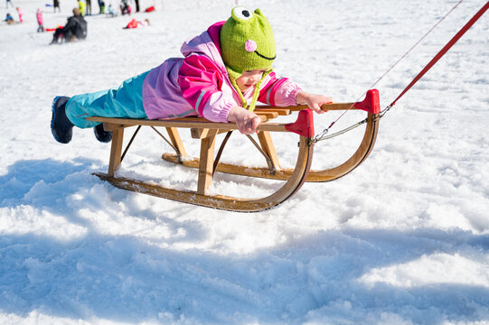 Cute Girl On A Sledge Being Pulled By Her Mother.