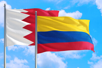 Colombia and Bahrain national flag waving in the windy deep blue sky. Diplomacy and international relations concept.