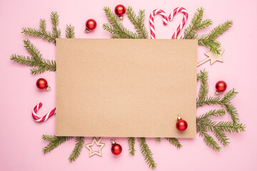 Paper blank, christmas tree branches, red balls decorations on pink pastel background. Christmas, New Year holiday mockup