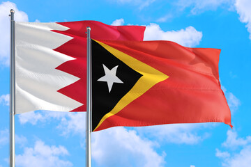 East Timor and Bahrain national flag waving in the windy deep blue sky. Diplomacy and international relations concept.