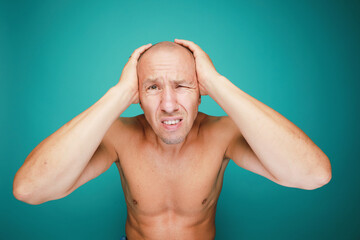  A bald man with headache isolated on green background